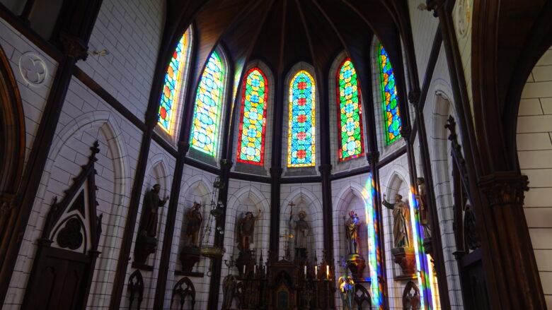 ステンドグラスから差し込む陽光の下に聖像が並ぶ