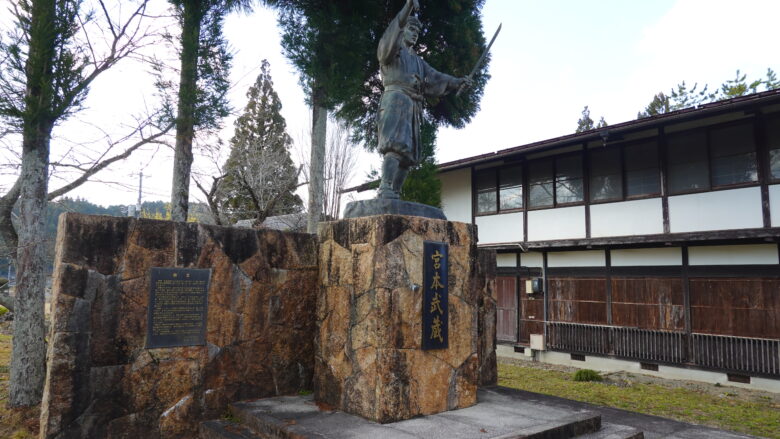 青年時代の武蔵の銅像、奥に見える建物は武蔵道場