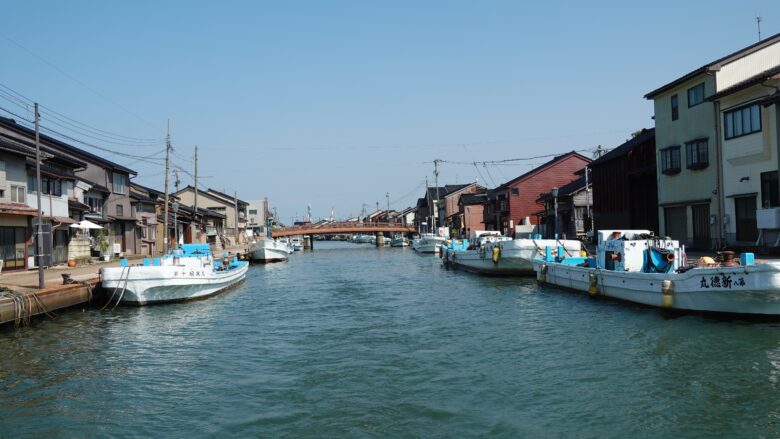 川岸に漁船が並ぶ中、その中央を突き進む